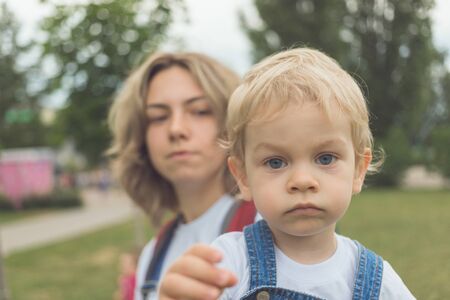 mom and her son walk in the park in identical denim jumpsuits. they enjoy time together and love each other. High quality photoの写真素材