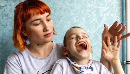 Boy with cerebral palsy and his mom in the conditions of his apartment. Boy reacts vividly to...