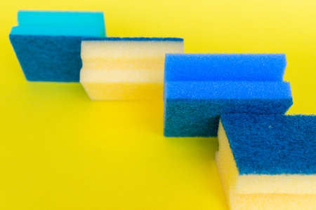 Dish washing sponges of different colors are on a yellow background. High quality photoの写真素材