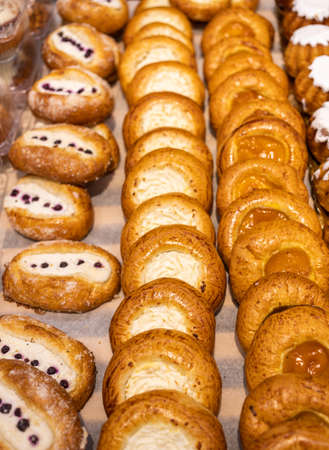 A lot of buns with different fillings and toppings are on the counter.の写真素材