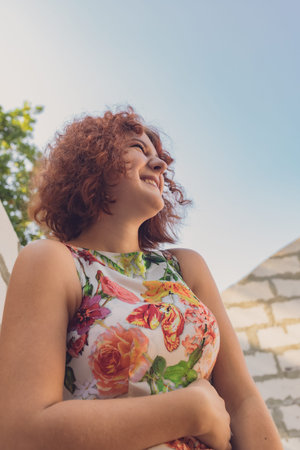 red-haired curly-haired girl in a summer dress posing in the village . High quality photo