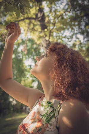 red-haired curly-haired girl in a summer dress posing in the village . High quality photoの写真素材