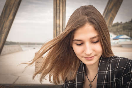 a beautiful young girl in a checked jacket and beige trousers poses for the camera in a Park. professional model with long hair. High quality photoの写真素材