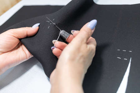 The dressmaker will open the fabric for the future costume for further work. Fashion designer tailor in the workshop of the studio, developing a new collection of clothes.の写真素材