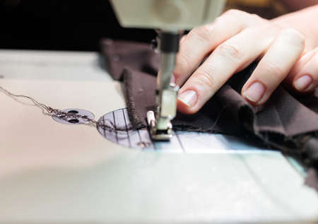 The dressmaker will open the fabric for the future costume for further work. Fashion designer tailor in the workshop of the studio, developing a new collection of clothes.の写真素材