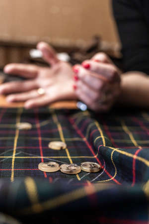 The dressmaker will open the fabric for the future costume for further work. Fashion designer tailor in the workshop of the studio, developing a new collection of clothes.の写真素材