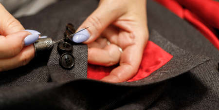 The dressmaker will open the fabric for the future costume for further work. Fashion designer tailor in the workshop of the studio, developing a new collection of clothes.の写真素材