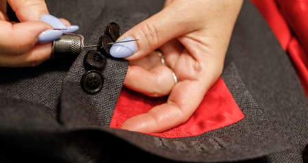 The dressmaker will open the fabric for the future costume for further work. Fashion designer tailor in the workshop of the studio, developing a new collection of clothes.の写真素材