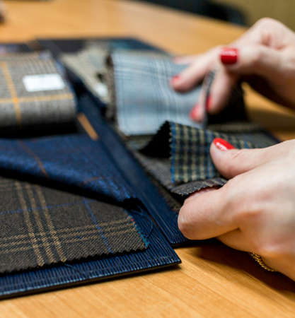 The dressmaker will open the fabric for the future costume for further work. Fashion designer tailor in the workshop of the studio, developing a new collection of clothes.の写真素材