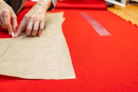 The dressmaker will open the fabric for the future costume for further work. Fashion designer tailor in the workshop of the studio, developing a new collection of clothes.の写真素材