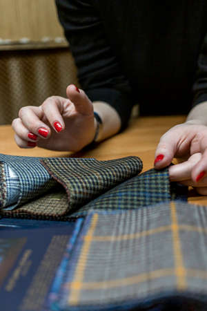 The dressmaker will open the fabric for the future costume for further work. Fashion designer tailor in the workshop of the studio, developing a new collection of clothes.の写真素材