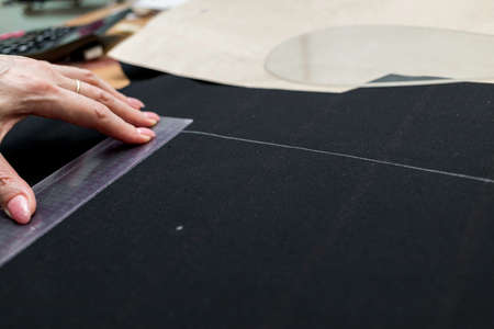 The dressmaker will open the fabric for the future costume for further work. Fashion designer tailor in the workshop of the studio, developing a new collection of clothes.の写真素材