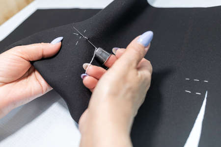 The dressmaker will open the fabric for the future costume for further work. Fashion designer tailor in the workshop of the studio, developing a new collection of clothes.の写真素材