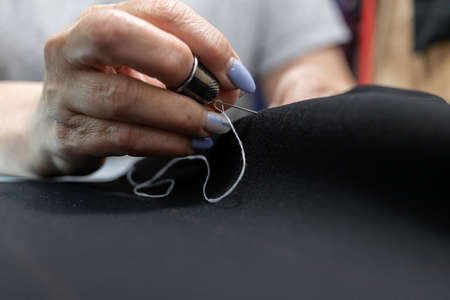The dressmaker will open the fabric for the future costume for further work. Fashion designer tailor in the workshop of the studio, developing a new collection of clothes.の写真素材