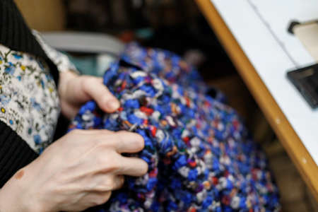 The dressmaker will open the fabric for the future costume for further work. Fashion designer tailor in the workshop of the studio, developing a new collection of clothes.の写真素材