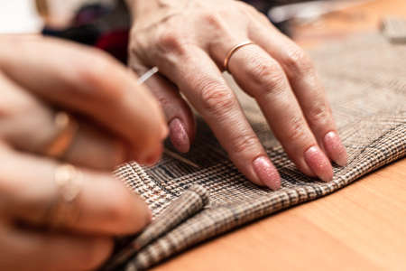 The dressmaker will open the fabric for the future costume for further work. Fashion designer tailor in the workshop of the studio, developing a new collection of clothes.の写真素材