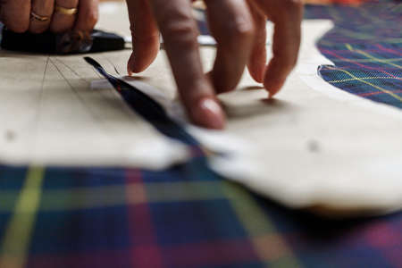 The dressmaker will open the fabric for the future costume for further work. Fashion designer tailor in the workshop of the studio, developing a new collection of clothes.の写真素材