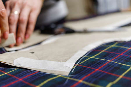 The dressmaker will open the fabric for the future costume for further work. Fashion designer tailor in the workshop of the studio, developing a new collection of clothes.の写真素材