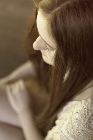 Teen girl with long brown hair in relaxed pose looking down at her lapの写真素材