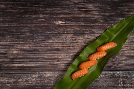 Sushi set of salmon nigiri on leaf on wooden background. Top view with copy spaceの写真素材