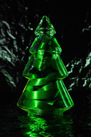 Christmas tree made of glass. Christmas and New Year Holidays concept. Shiny bright green Christmas decoration on dark background close upの写真素材
