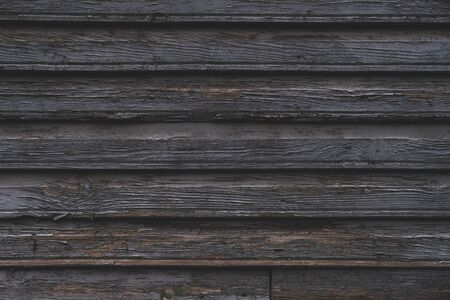 Dark wooden texture background. Old wall with peeled off gray paint surface. Horizontal wooden boards. Close up with copy spaceの写真素材