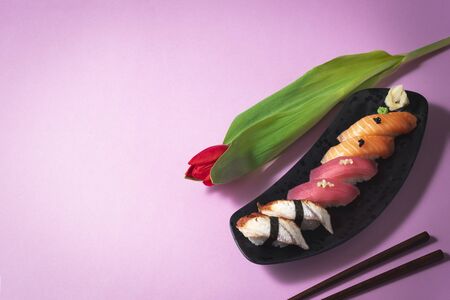 Sushi set with flower on pink background. Salmon, tuna and eel sashimi nigiri. Valentines Day (February 14), Mother's day, Woman's day (8 March), date or spring concept. Japanese food. Copy spaceの写真素材