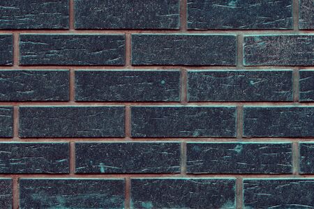 Black beautiful new toned brick wall texture background. Dark bricks with orange and green stucco. Modern building wall material. Close up, copy spaceの写真素材