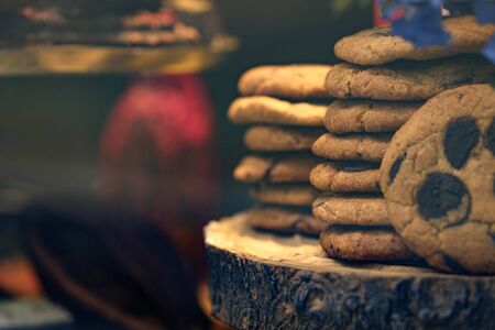 Chocolate chip cookies on wooden board through cafe window with blurred background. Cozy cafe showcase. Selective focus, copy spaceの写真素材