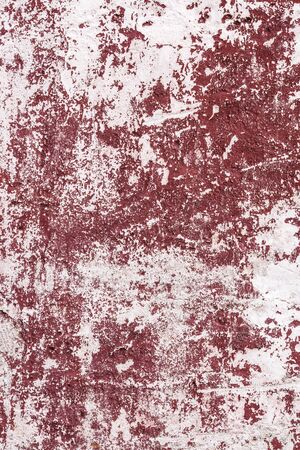 Abstract grunge texture of old red and white wall with peeled off paint. Creative background. Beautiful rough weathered stone texture. Vertical, copy spaceの写真素材