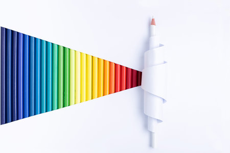 One white pencil in curled paper on white cut background with colored pencils.
