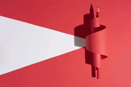 One red pencil in curled paper on red Ñut background.
