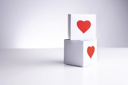 Two white boxes with red hearts on a top of each other on a white background, close up, copy space.の写真素材