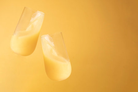 Two glasses with fresh orange juice on a yellow background, close up, copy space.の写真素材