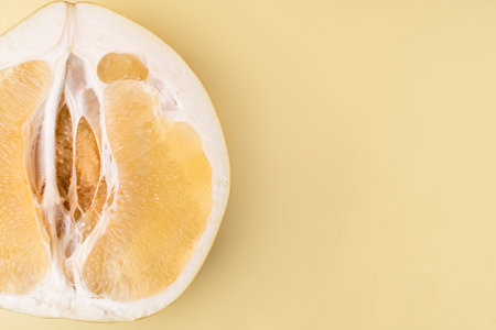 Half of juicy fresh pomelo, orange on a yellow background, close up, copy space.の写真素材