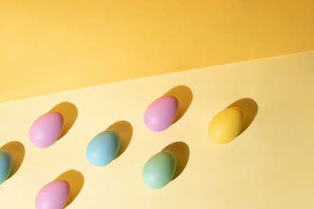 Multicolored Easter eggs on a yellow background in sunlight. Modern isometric concept. Easter background.の写真素材