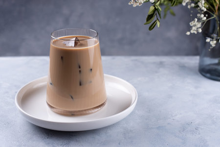 Iced coffee latte on a gray background. Coffee with milk and ice cubes, close up