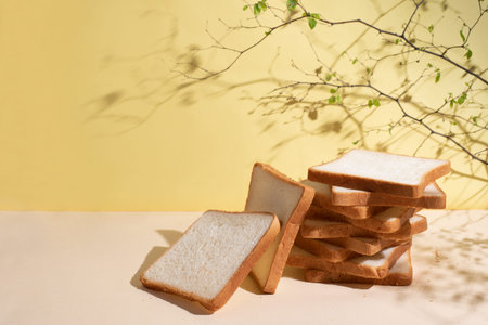 Sliced toast bread on a yellow background in sunlight with beautiful shadows, close up.