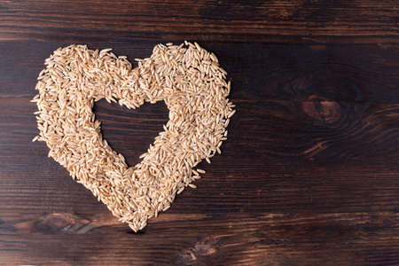 Heart of oatmeal on a wooden background, healthy food concept, close up.の写真素材