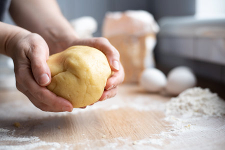 Female hands holding a bowl of cookie dough in the kitchen, cooking cookies at home, close up.