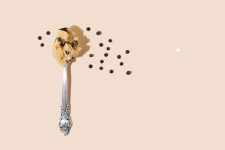 Edible cookie dough in spoon with chocolate chips on the yellow background in sunlight, close up.の写真素材