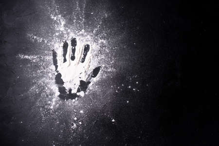 Handprint in wheat flour on a black background, close up, copy space.の写真素材