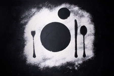 Imprints of cutlery in wheat flour, traces of serving dishes, black background, close up.