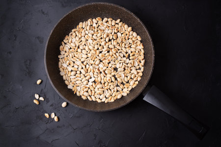 Roasted fresh peanuts in a frying pan on a black background, close up.の写真素材