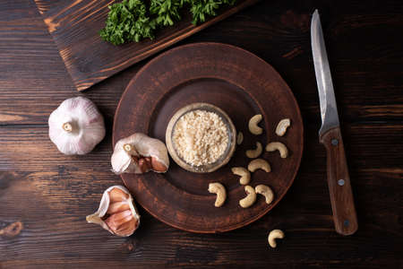 Vegan parmesan cheese cashew nut with parsley and garlic cloves on a wooden background, vegan food, close up.の写真素材