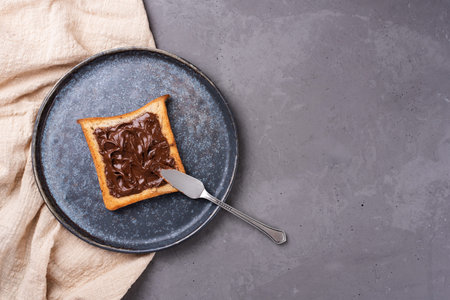 Toast with chocolate paste on a plate on a gray concrete background with textile, copy space.
