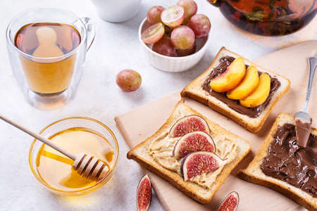 Toast with chocolate spread, peanut butter peach and figs on a white table served for breakfast, a healthy dessert.の写真素材