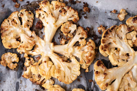 Grilled slices of cauliflower on baking parchment, baked vegetables, healthy vegetarian food.の写真素材