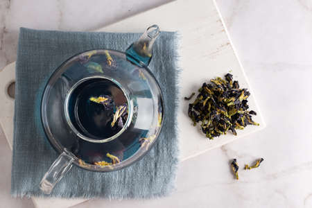 Glass teapot with butterfly pea flower tea, blue anchan on marble background, top view.の写真素材
