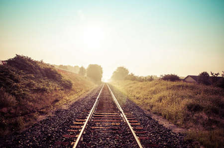 Looking town the train tracks as the sun rises behind the fog.の写真素材